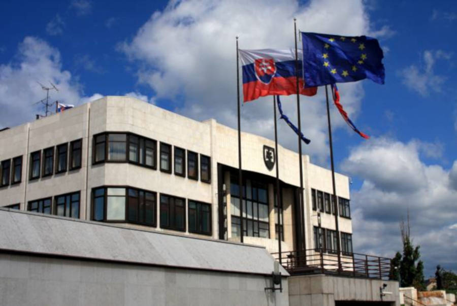 Slovakia's Parliament during the day with European and Slovakian banners out front.