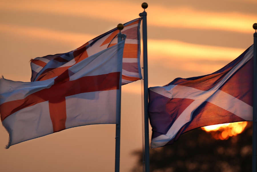 The flags of UK member countries at sunset.